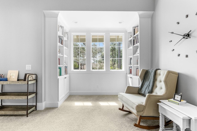 living area featuring light carpet and baseboards