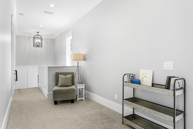 living area with visible vents, baseboards, ornamental molding, carpet floors, and a chandelier