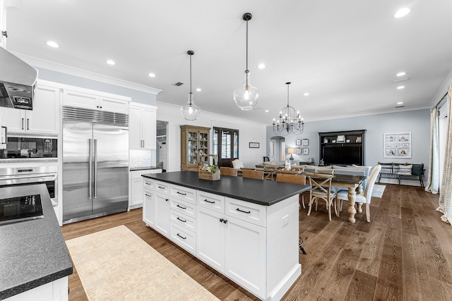 kitchen with built in appliances, decorative backsplash, dark wood-style floors, dark countertops, and crown molding