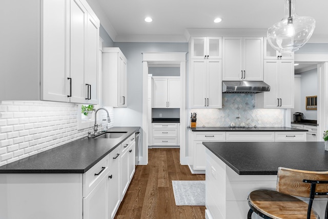 kitchen with dark wood-style floors, dark countertops, white cabinets, a sink, and under cabinet range hood