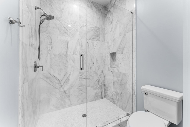 bathroom with toilet and a marble finish shower