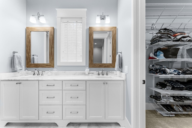 full bath featuring a walk in closet, a sink, and double vanity