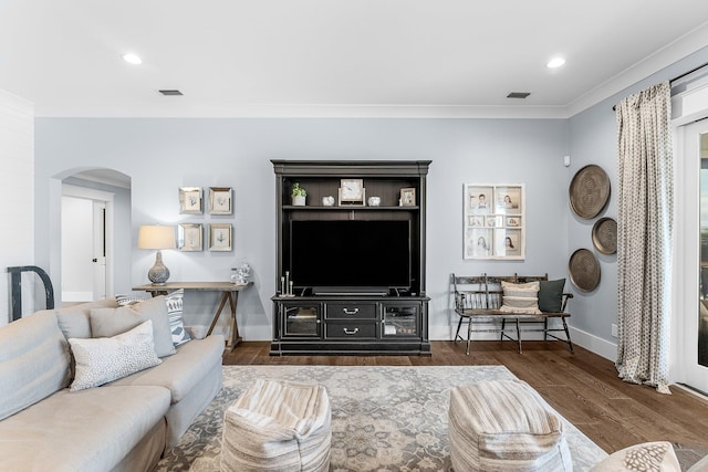 living room with arched walkways, ornamental molding, wood finished floors, and visible vents