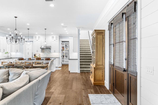 foyer entrance featuring recessed lighting, dark wood-type flooring, stairway, an inviting chandelier, and crown molding