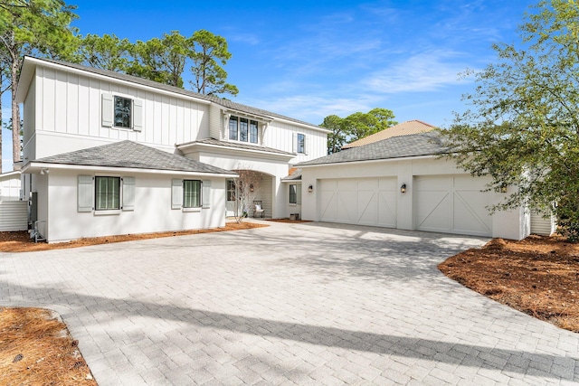 view of front of property featuring an attached garage, board and batten siding, decorative driveway, and roof with shingles