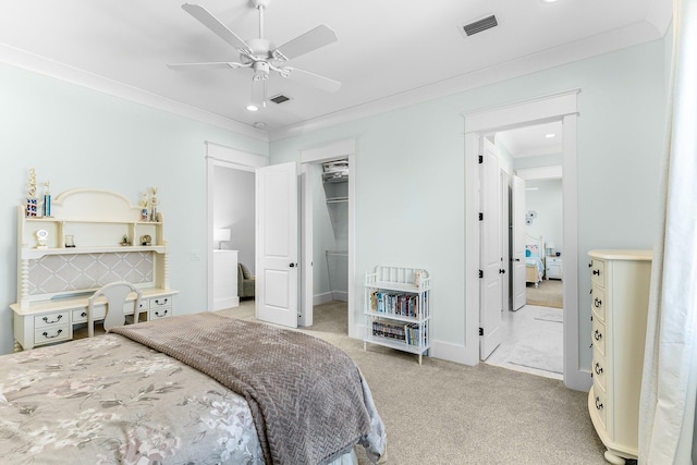 bedroom featuring crown molding, a spacious closet, visible vents, and light colored carpet