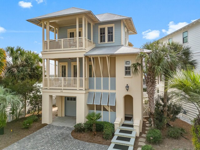 raised beach house featuring a garage and a balcony