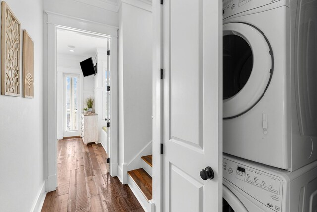 washroom featuring stacked washer / dryer and dark wood-type flooring