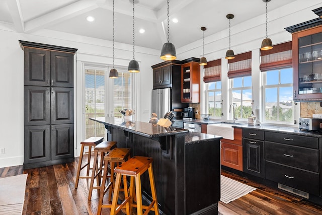 kitchen with sink, a kitchen island, dark wood-type flooring, and plenty of natural light