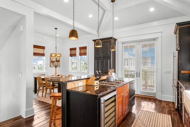 kitchen with beverage cooler, a kitchen breakfast bar, dark hardwood / wood-style flooring, dark stone counters, and a kitchen island