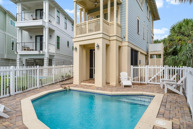 rear view of house featuring a fenced in pool, a balcony, and a patio