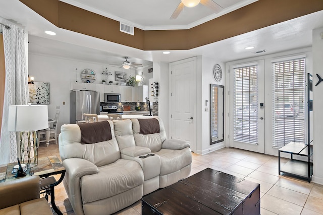 living room featuring light tile patterned floors, ceiling fan, and ornamental molding