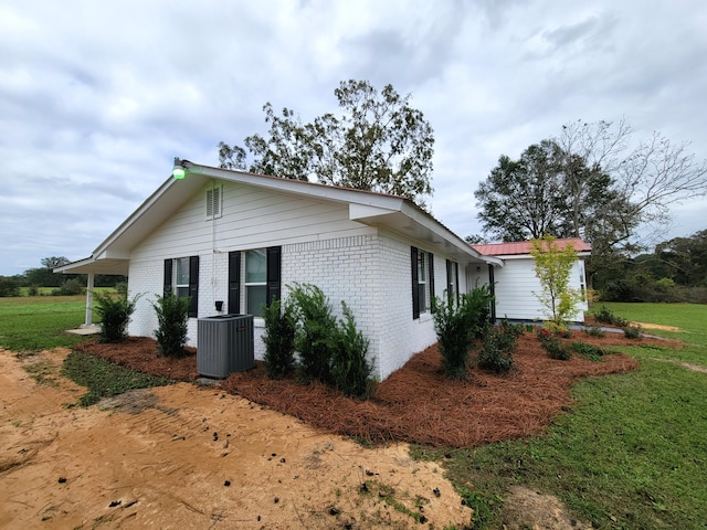 view of side of property featuring central AC and a lawn