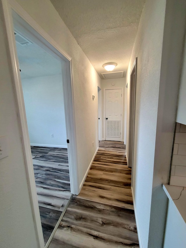 hall featuring wood-type flooring and a textured ceiling