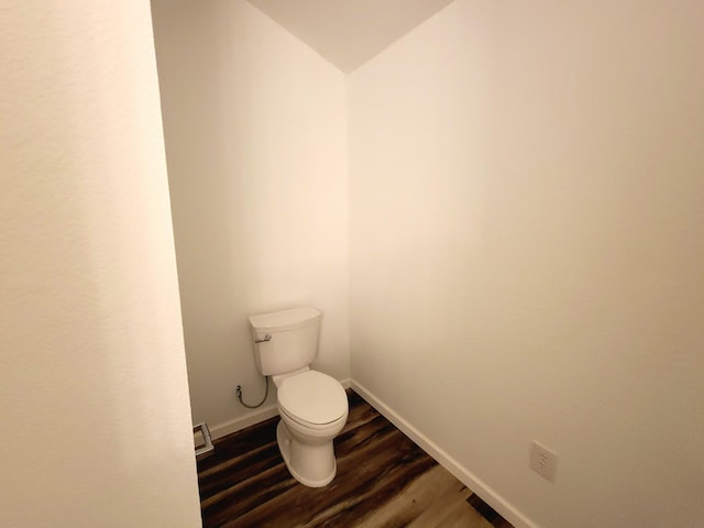 bathroom with wood-type flooring, vaulted ceiling, and toilet