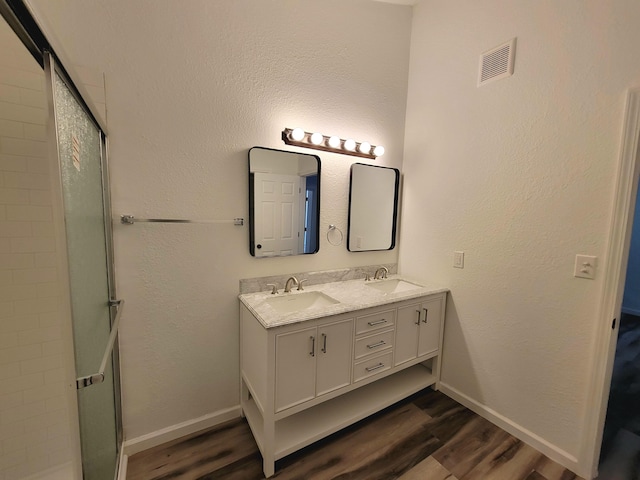 bathroom with wood-type flooring, vanity, and walk in shower