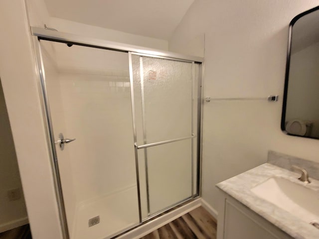 bathroom with vanity, a shower with shower door, hardwood / wood-style flooring, and lofted ceiling