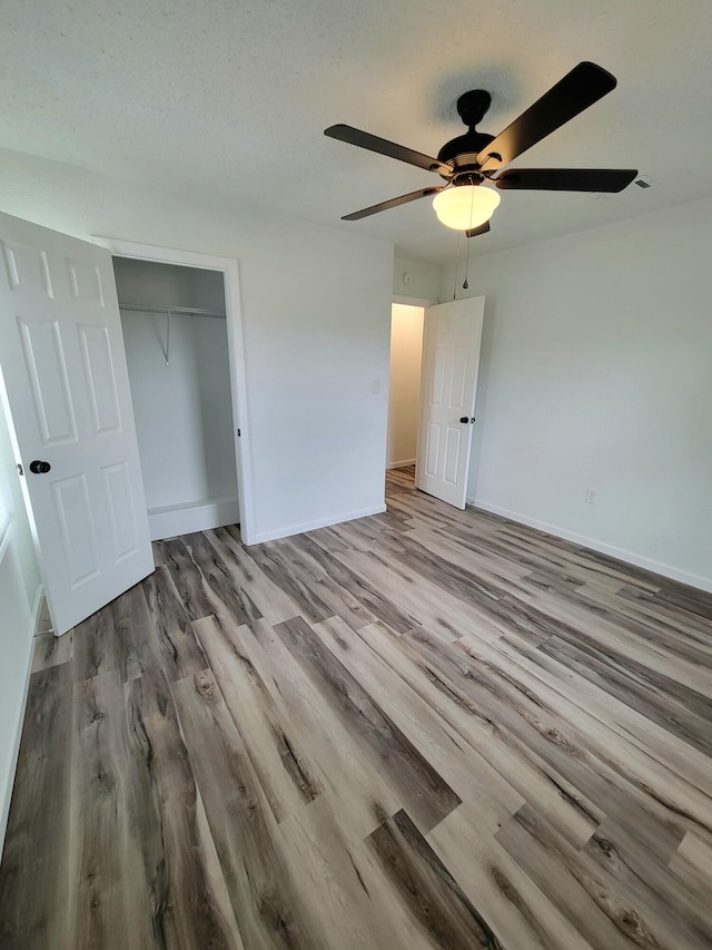 unfurnished bedroom with a closet, ceiling fan, light wood-type flooring, and a textured ceiling