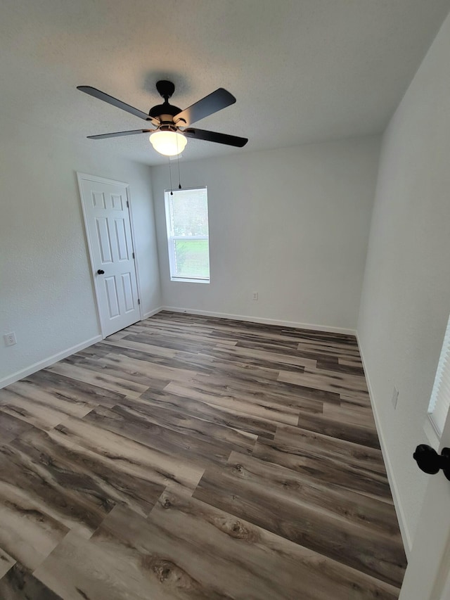 unfurnished room with ceiling fan and dark hardwood / wood-style flooring