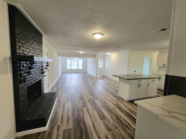 unfurnished living room with a fireplace, hardwood / wood-style floors, and a textured ceiling