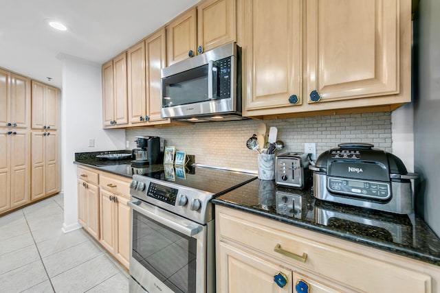 kitchen with light tile patterned floors, stainless steel appliances, and dark stone countertops