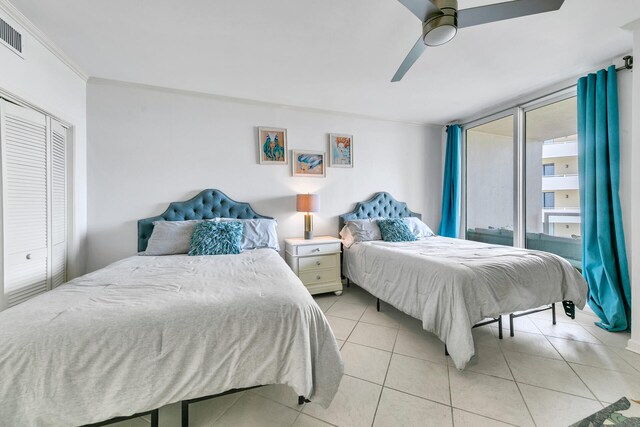 bedroom featuring a closet, ceiling fan, light tile patterned floors, and crown molding