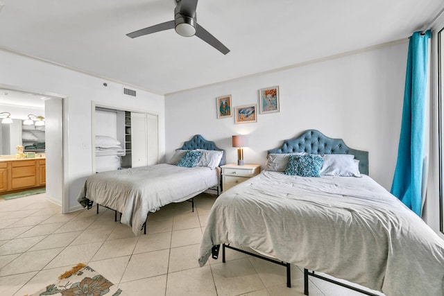 tiled bedroom with a closet, ceiling fan, crown molding, and ensuite bathroom