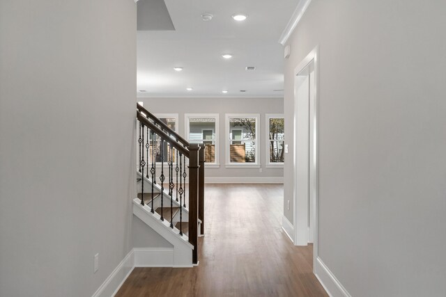 corridor with wood-type flooring and ornamental molding