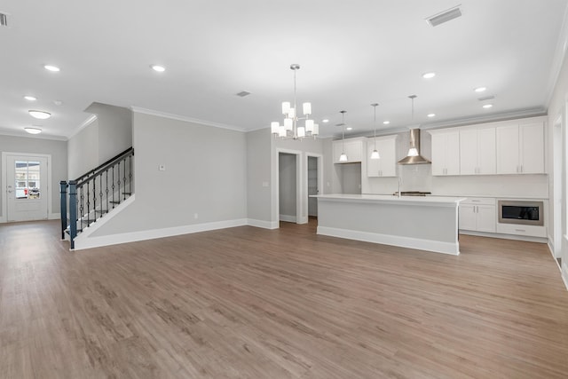 unfurnished living room featuring crown molding, light hardwood / wood-style flooring, and a notable chandelier