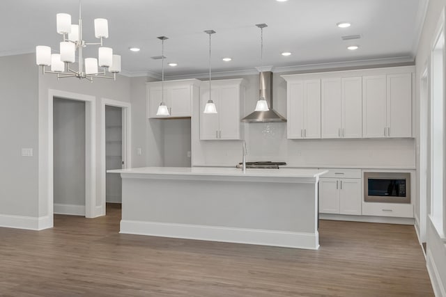 kitchen featuring white cabinetry, a center island with sink, wall chimney exhaust hood, and pendant lighting