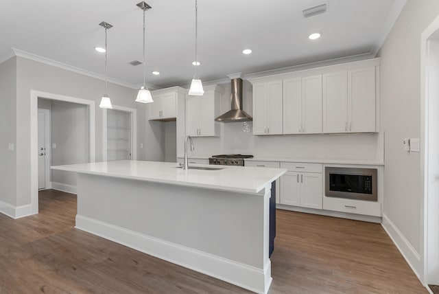 kitchen with pendant lighting, white cabinetry, wall chimney exhaust hood, and sink