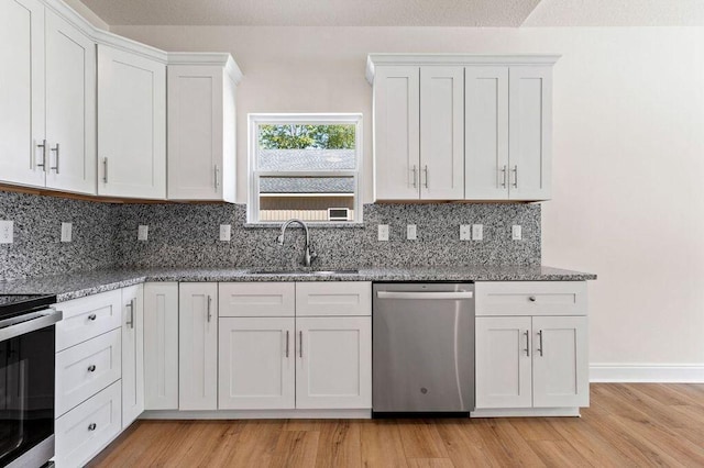 kitchen with backsplash, dark stone counters, light hardwood / wood-style floors, white cabinets, and appliances with stainless steel finishes