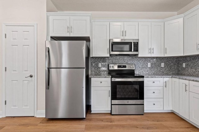 kitchen with white cabinets, appliances with stainless steel finishes, light hardwood / wood-style floors, and decorative backsplash