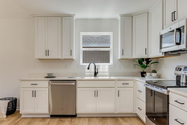 kitchen featuring white cabinetry, sink, light hardwood / wood-style flooring, and appliances with stainless steel finishes