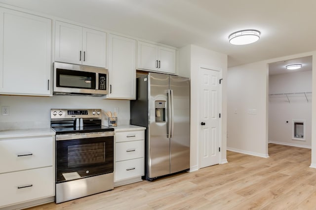 kitchen with appliances with stainless steel finishes, light hardwood / wood-style floors, and white cabinets