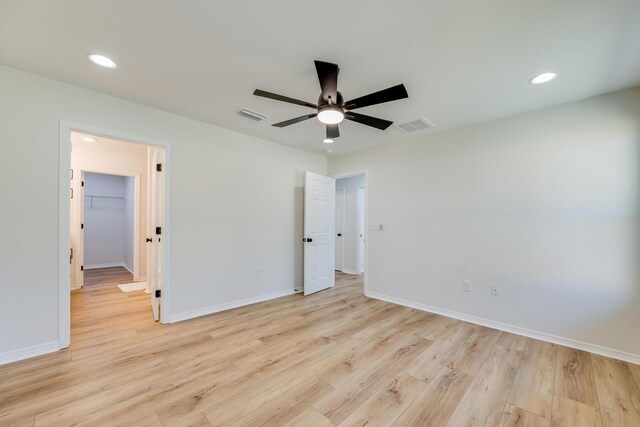 unfurnished bedroom featuring ceiling fan, a spacious closet, and light hardwood / wood-style floors