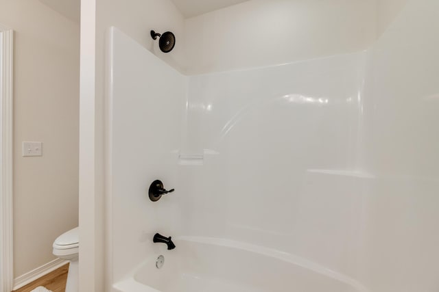 bathroom with shower / bathtub combination, wood-type flooring, and toilet