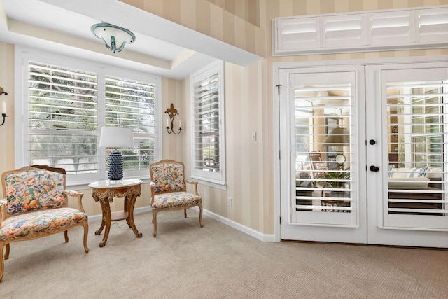 sitting room featuring french doors, light colored carpet, and a tray ceiling