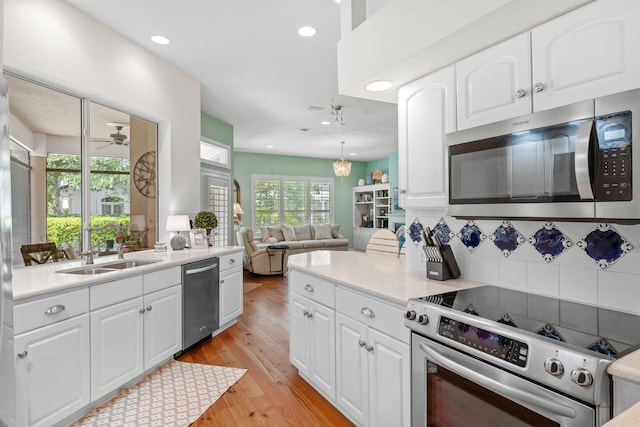 kitchen featuring white cabinets, decorative light fixtures, light hardwood / wood-style floors, and appliances with stainless steel finishes