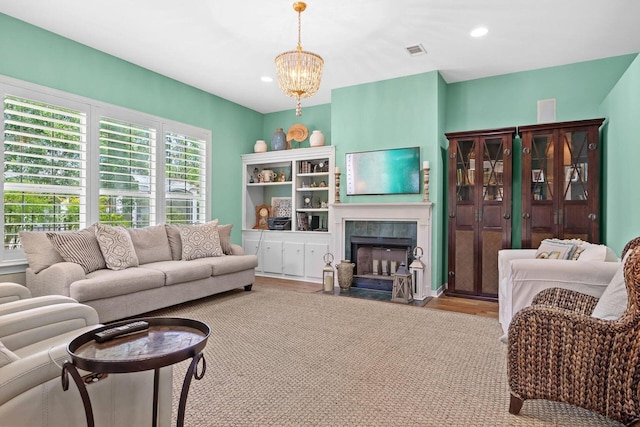 living room featuring a fireplace, light hardwood / wood-style flooring, and a notable chandelier