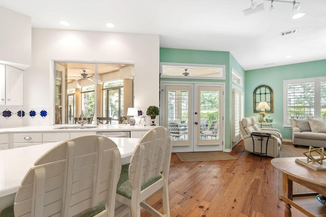 dining space featuring french doors, light hardwood / wood-style flooring, a healthy amount of sunlight, and sink