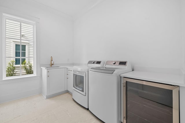 washroom with wine cooler, sink, washer and dryer, and ornamental molding