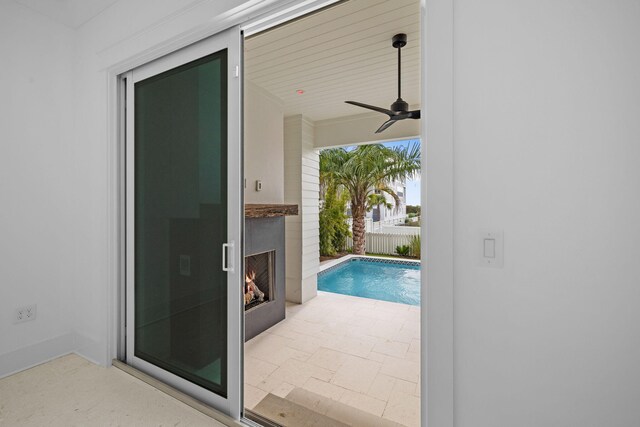 view of swimming pool featuring a patio area, ceiling fan, and exterior fireplace