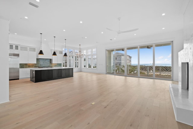 unfurnished living room featuring crown molding, light hardwood / wood-style floors, and ceiling fan with notable chandelier