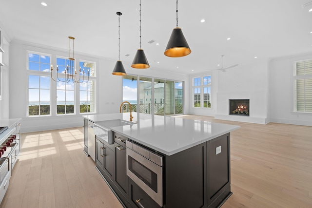 kitchen featuring decorative light fixtures, a kitchen island with sink, and a healthy amount of sunlight