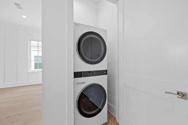 clothes washing area with stacked washer and dryer and light hardwood / wood-style floors