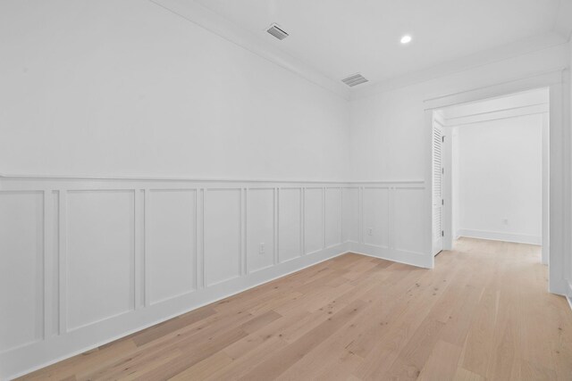 spare room with crown molding and light wood-type flooring