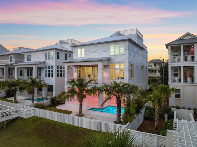 back house at dusk with a patio area and a fenced in pool