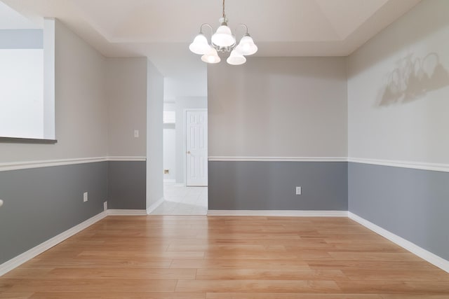 spare room with light hardwood / wood-style floors and an inviting chandelier