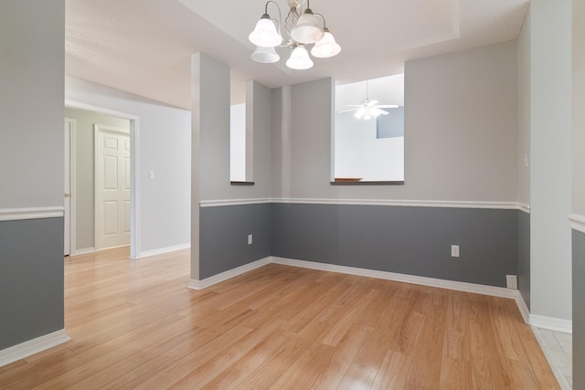 unfurnished room with a textured ceiling, ceiling fan with notable chandelier, and light hardwood / wood-style floors